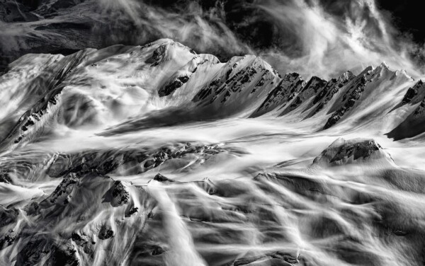 By Michael Piraino Black and white aerial of the snow-capped peaks of the Southern Alps in New Zealand