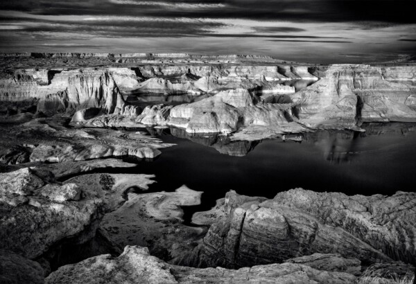 By Michael Piraino Lake shore with buttes and rock formations in black and white