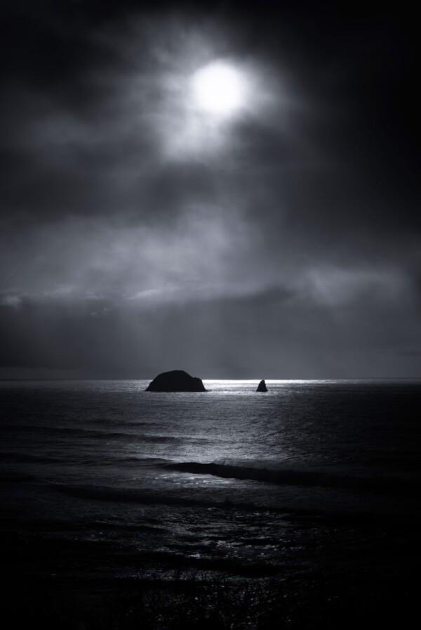 By Michael Piraino Moody black and white with sunbeams shining on small islands in the ocean