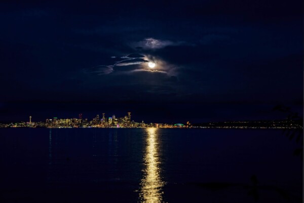 By Michael Piraino Moon rising through clouds at night over Seattle skylne