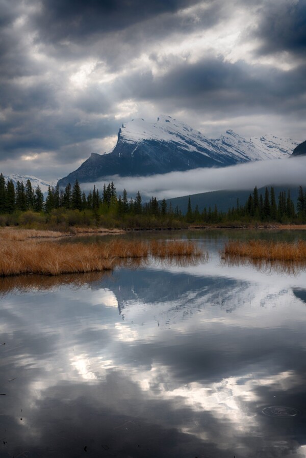 By Michael Piraino alpine lake in Canadian Rockies with fog, clouds and reflections in a lake