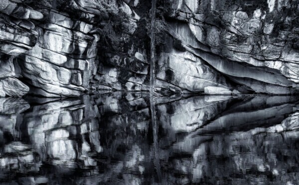 by MIchael Piraino Alpine lake with rock reflections in black and white