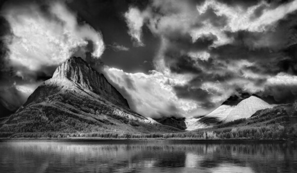 By Michael Piraino Black and white of mountains and clouds reflecting in a lake at Glacier National Park